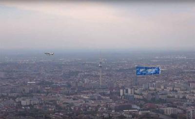 El avión y la pancarta con el cielo de Gernika sobrevolando Alexanderplatz, epicentro de la capital germana