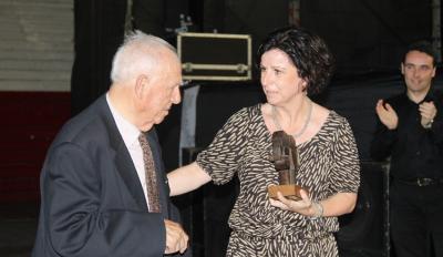 Isidro Legarreta recibe en 2014 de manos de Marian Elorza, secretaria general de Acción Exterior, el homenaje del Gobierno Vasco, mientras desde atrás aplaude Asier Vallejo, director para la Comunidad Vasca en el Exterior (foto EuskalKultura.com)