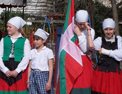 Las dantzaris txikis acompañando o portando  la ikurriña durante el acto de homenaje del sábado