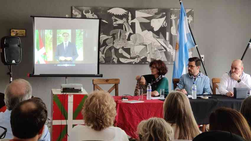 Siguiendo el video del lehendakari Pradales. En la mesa, Sara Pagola delegada de Euskadi en Argentina, Ander Caballero secretario general de Acción Exterior y Gorka Alvarez director para la Comunidad Vasca en el Exterior